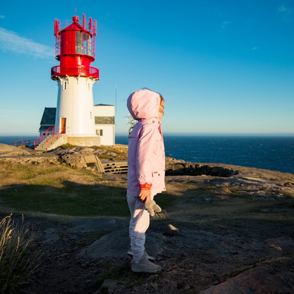 Barn foran fyret i lavt kveldslys – Lindesnes Fyr hos Tilbring i Agder.