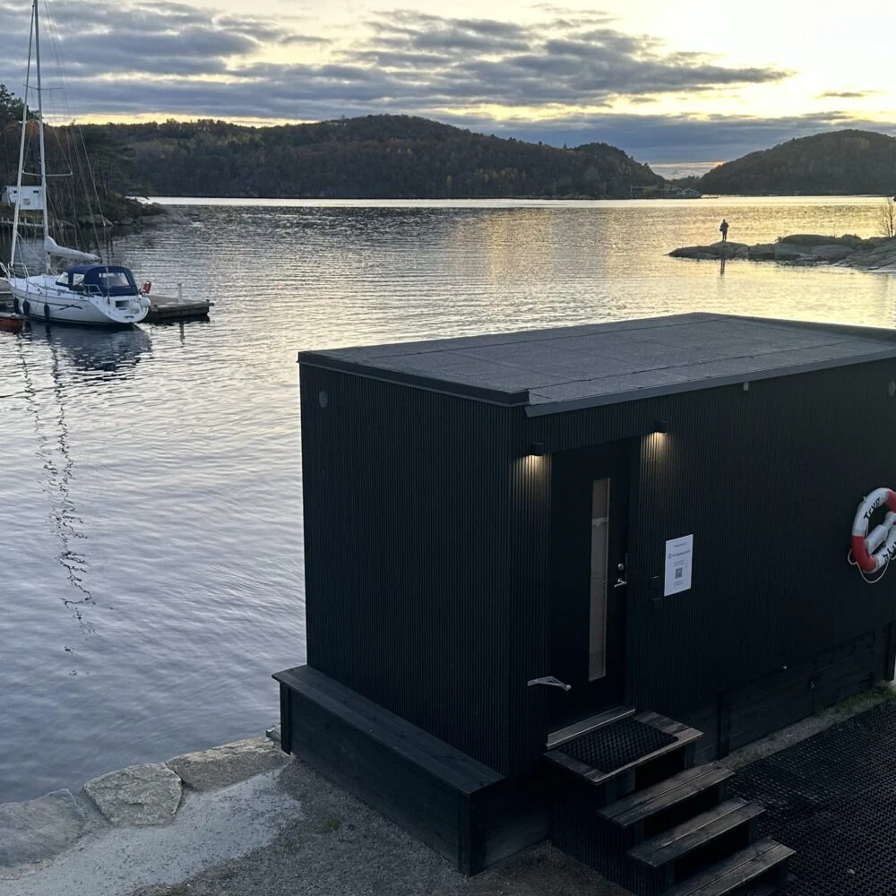 Badstua på brygga med seilbåter og solnedgang over fjorden – Smeigedag Sauna Mandal hos Tilbring i Agder. Rabattkode Tilbring gir 10 % rabatt.